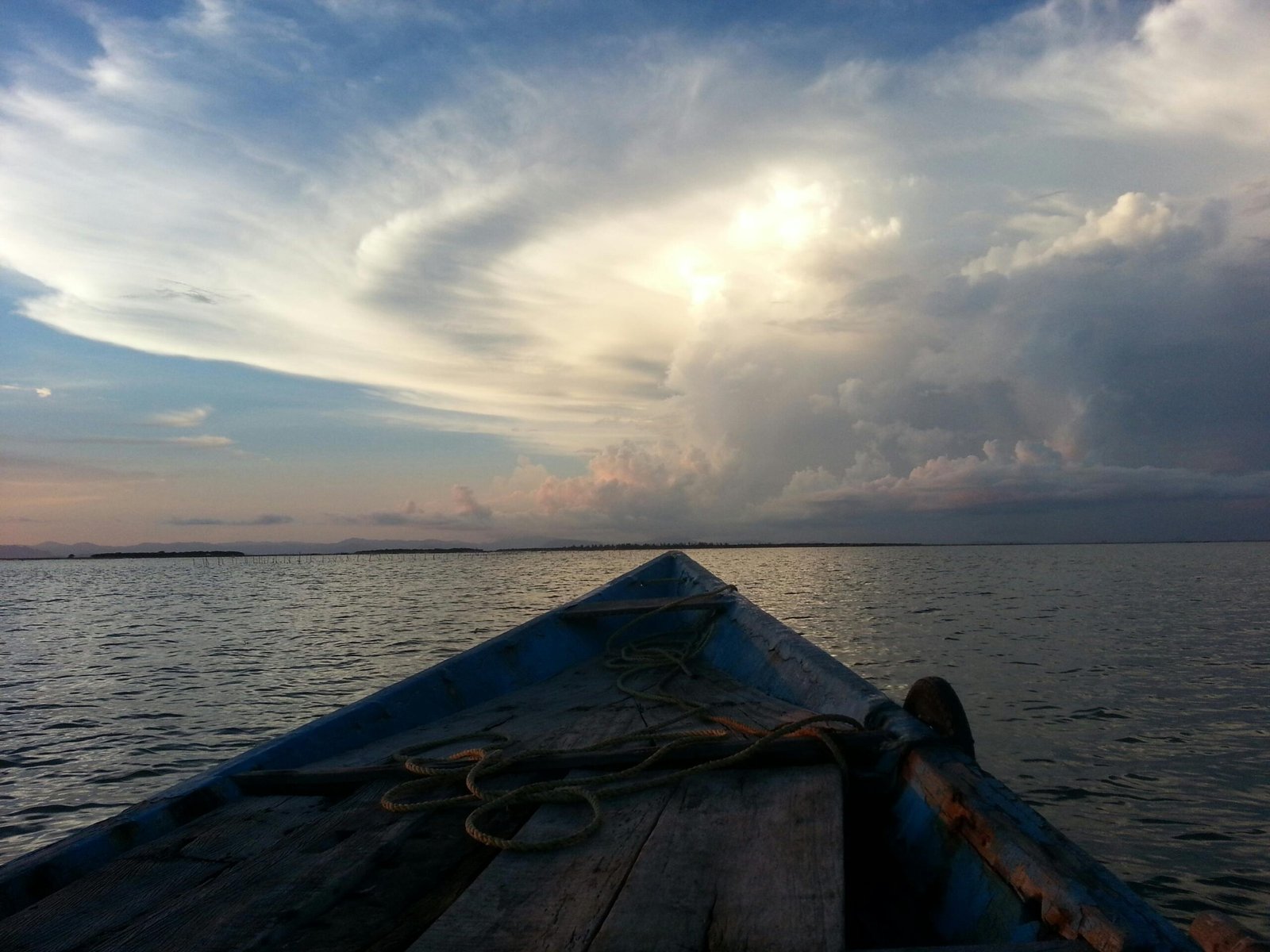 Tranquil evening scene of a boat on calm waters with dramatic clouds in Puri, India.